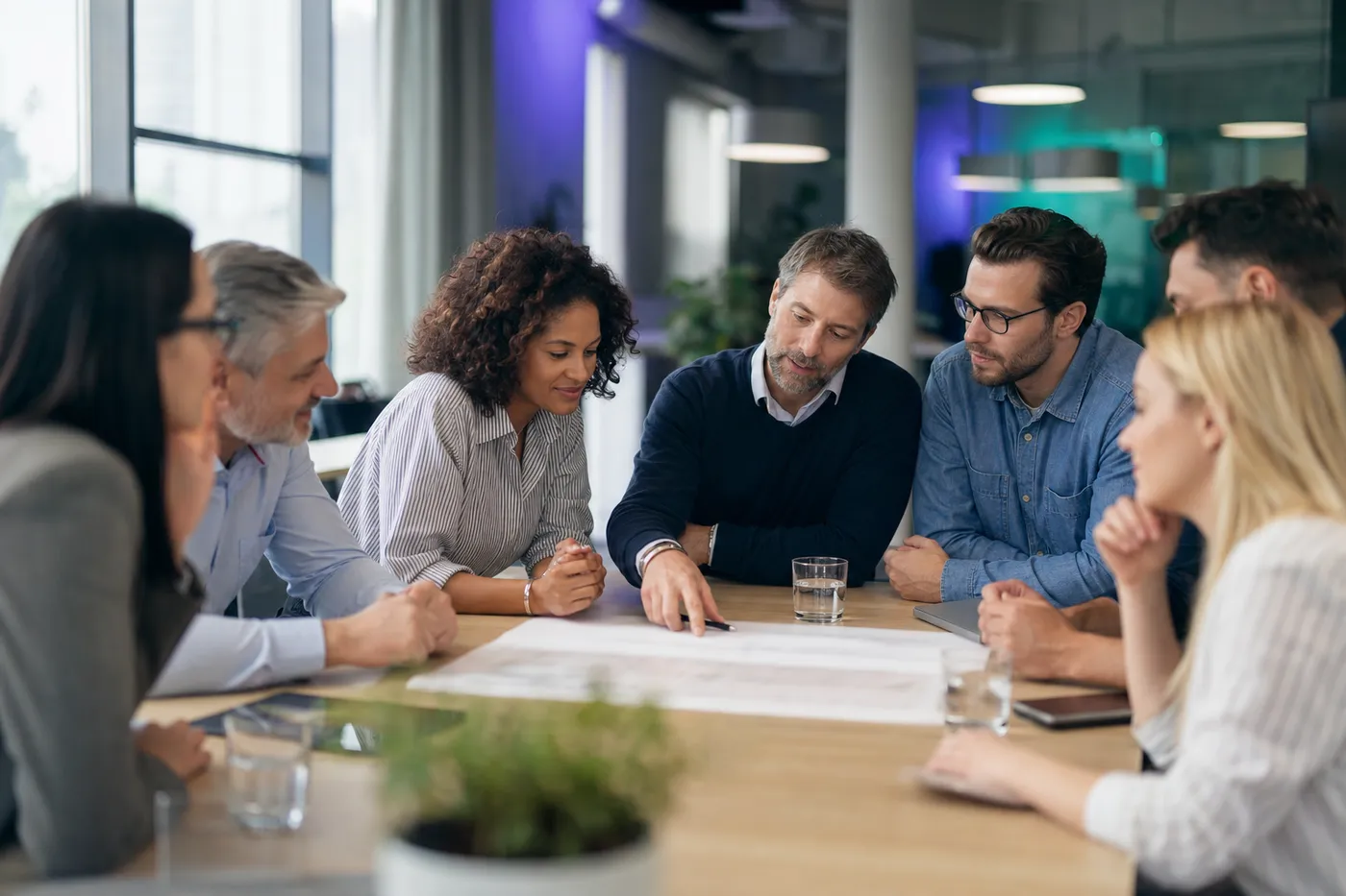 A small team in a bright office gathered around a table, discussing their team personality assessment together