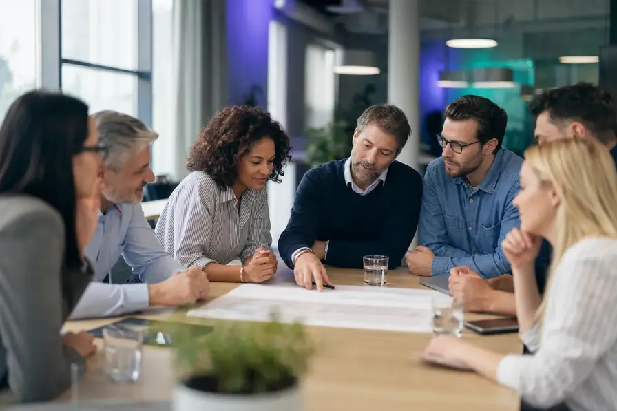 Six colleagues around a table reading their team personality map together during a debrief.